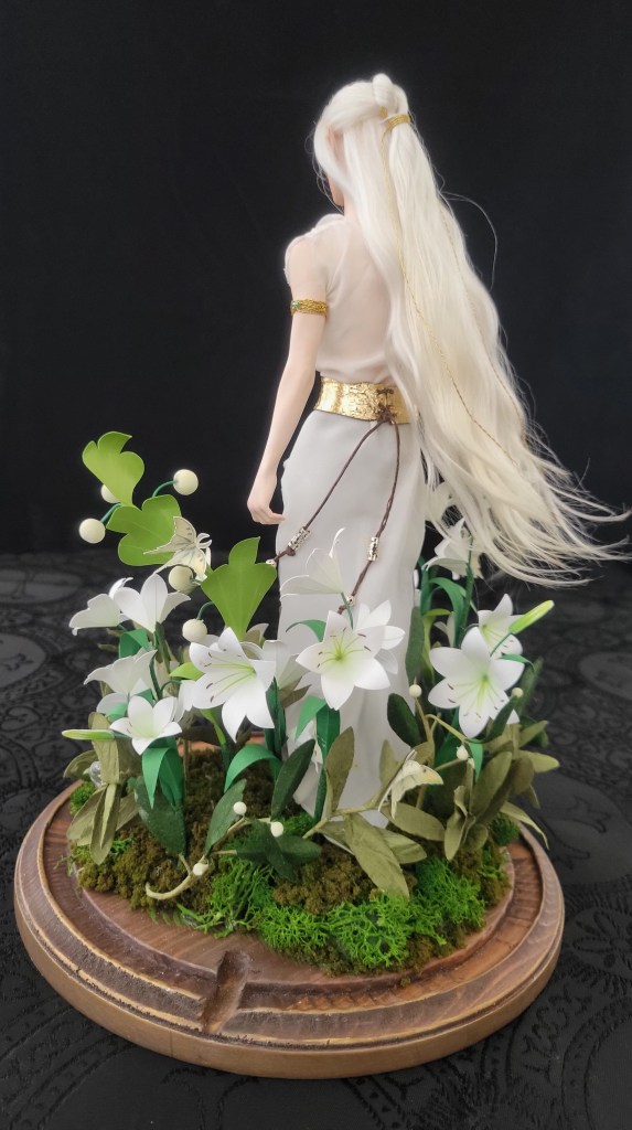 Remenaxice from Sufferborn and Elves Unwelcome as a 3d printed sculpture assembled under a glass dome with paper lilies and RGB lights.