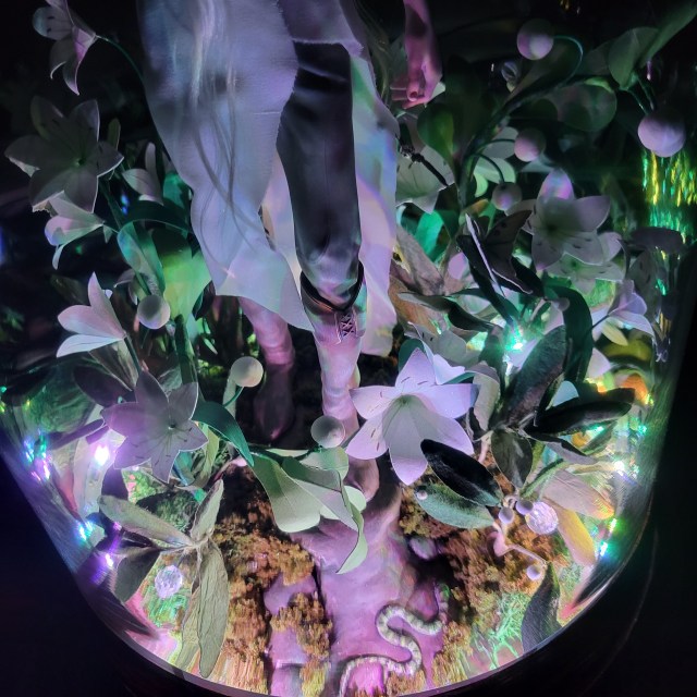 Remenaxice from Sufferborn and Elves Unwelcome as a 3d printed sculpture assembled under a glass dome with paper lilies and RGB lights.